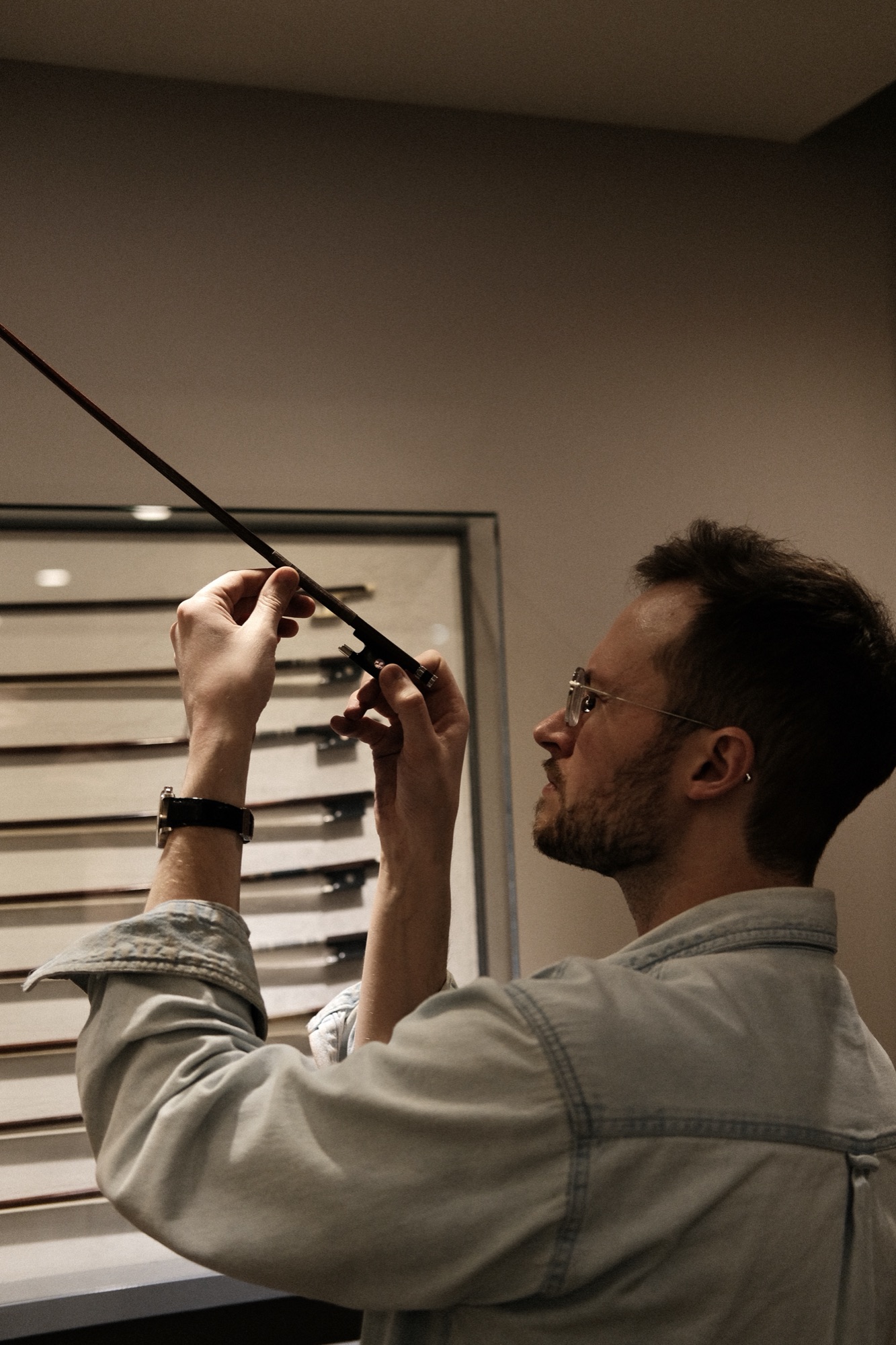 Sawyer Thomson examining a bow above a display case of fine bows