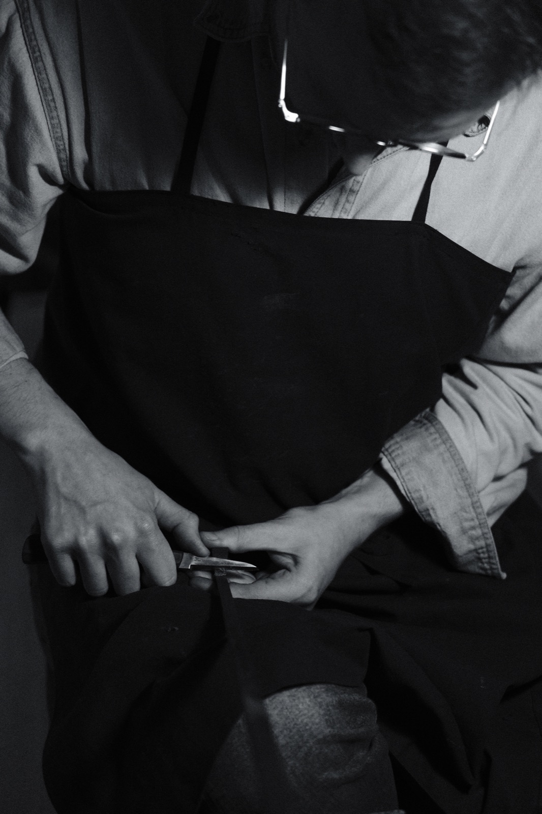 Hands shaping a bow with a knife at the bench